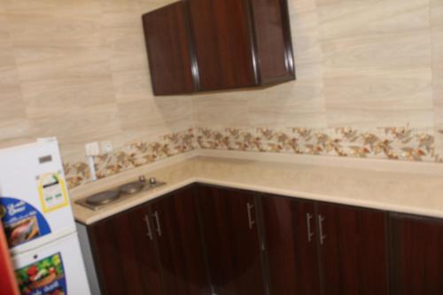 uma cozinha com armários castanhos, um lavatório e um frigorífico em Al Massah Al Khalijiyah Furnished Units em Dammam