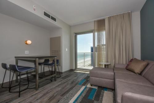 uma sala de estar com um sofá, uma mesa e uma varanda em Residence Inn by Marriott Myrtle Beach Oceanfront em Myrtle Beach