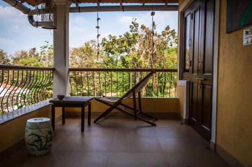 a room with a balcony with a chair and a window at Serendipity House Goa in Nerul
