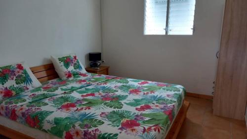 a bedroom with a bed with a floral comforter and a window at Zowanj 1 - Logement avec vue panoramique in Le Robert