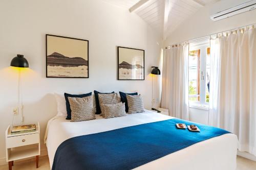 a white and blue bedroom with a large bed at Jubarte Hotel by Insólito in Búzios
