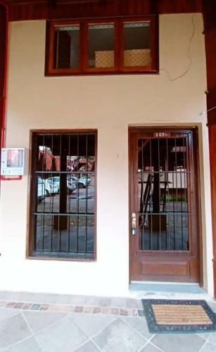 two doors on a white building with iron gates at Chalé esquina da CATEDRAL de Canela in Canela