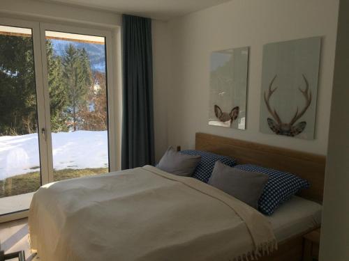 Schlafzimmer mit einem Bett und einem Fenster mit Geweihen in der Unterkunft Exklusive Ferienwohnung am Prielerweg in Hinterstoder in Hinterstoder