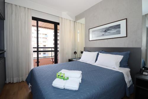 1 dormitorio con 1 cama azul y 2 toallas en Flat Centro de Brasilia, en Brasilia