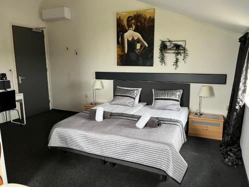 a bedroom with a large bed and a painting on the wall at Hotel Dijkzicht in Oudeschip