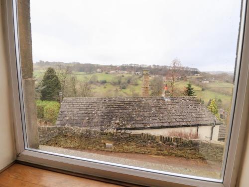 a window with a view of a stone building at Rivendell in Holmfirth