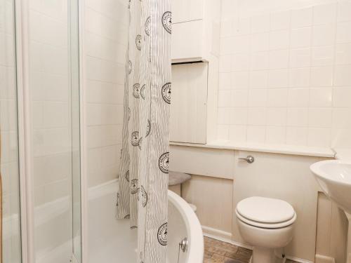 a white bathroom with a toilet and a shower at Rivendell in Holmfirth