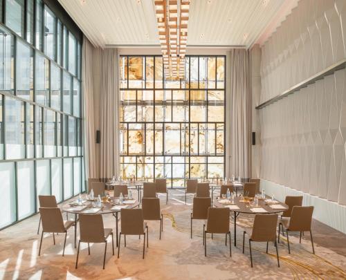 a dining room with tables and chairs and large windows at Le Meridien Bangkok in Bangkok