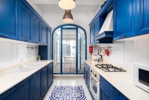 a blue kitchen with white counters and blue cabinets at Chic, Stylish Traditional Townhouse with Terrace - St. Paul’s Bay in St Paul's Bay