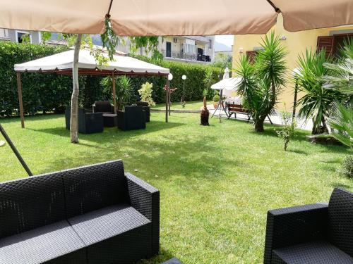 um pátio com cadeiras e um guarda-sol e relva em Appartamento in B&B Vesuvio em SantʼAntonio Abate