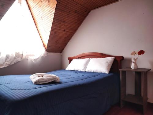 a bedroom with a bed with a blue blanket and a window at Alojamiento Chalet - Monguí in Monguí