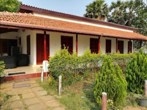 ein Haus mit roten Türen und einem Garten mit Bäumen in der Unterkunft Sun & Sand Guest House in Mullaittivu