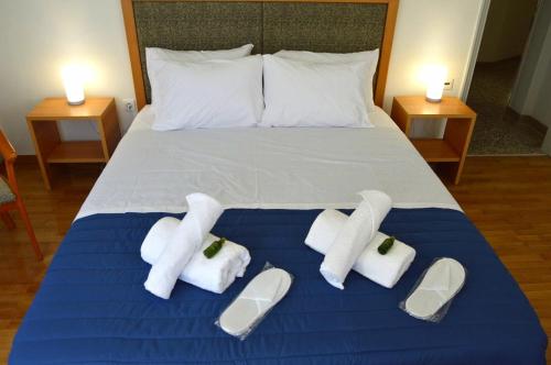 a bed with white towels and slippers on it at EstellApartments in Athens