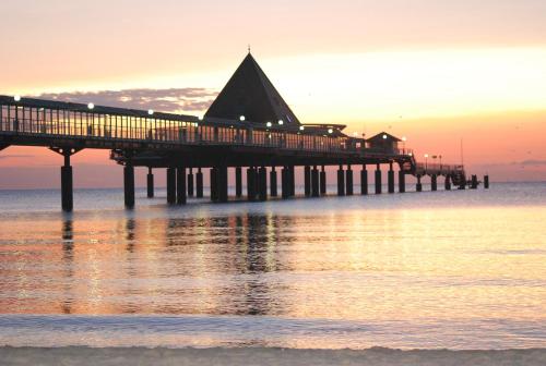 a pier on the water at sunset at Hotel Wald und See in Heringsdorf