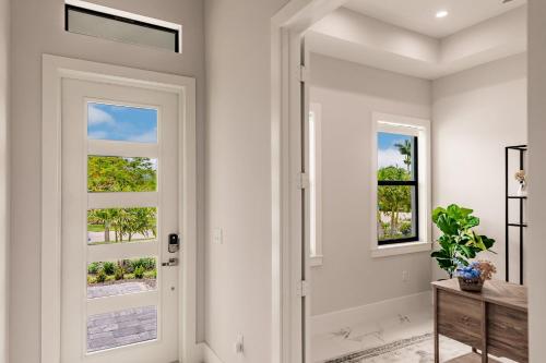 a hallway with white walls and a door with windows at Brand New Luxury Naples 4br W Pool By Vanderbilt Beach Coastal Sol By Boutiq in Naples