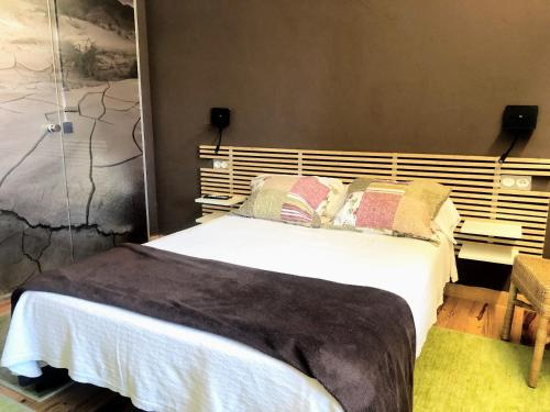 a bedroom with a large bed with white sheets and pillows at Hostal Rural Txapi Txuri Logis Hotels in Murillo el Fruto
