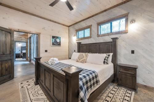 a bedroom with a bed in a room with wooden walls at Fun & Inviting Modern Luxury 4br Retreat At Broken Bow Lake Features Hot Tub, Fire Pit, Playground And More Once In A Blue Moon By Boutiq in Broken Bow