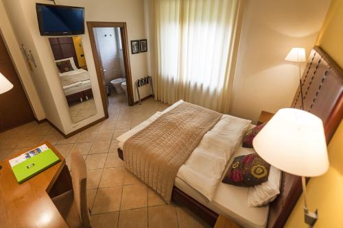 a small bedroom with a bed and a mirror at Hotel Meridiana in Malcesine