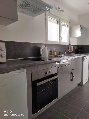 une cuisine avec un évier et une cuisinière four supérieur dans l'établissement Joli T1 hypercentre Rochefort, à Rochefort