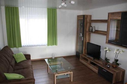 a living room with a couch and a television and green curtains at Ferienwohnung am Nibelungensteig in Lautertal