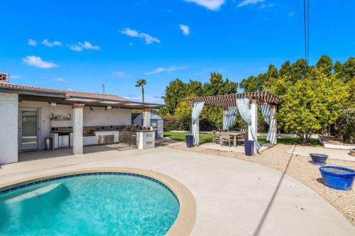 a backyard with a swimming pool and a pergola at The Sunny Side House in Palm Springs