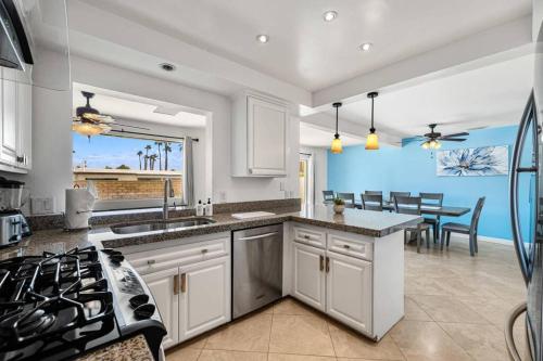 a kitchen with white cabinets and a dining room with a table at The Sunny Side House in Palm Springs