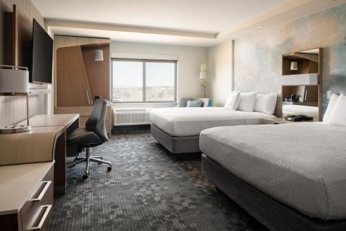 a hotel room with two beds and a desk at Courtyard by Marriott Loveland Fort Collins in Loveland