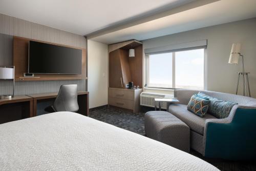 a hotel room with a bed and a chair and a television at Courtyard by Marriott Loveland Fort Collins in Loveland