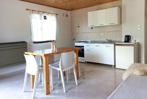 cocina con mesa de madera y sillas blancas en Los Guindos en El Calafate