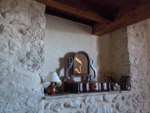 a stone wall with a mirror and a lamp on a shelf at La Casa Sù Le Dimore Del Borgo in Santo Stefano di Sessanio