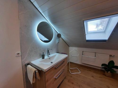 La salle de bains est pourvue d'un lavabo, d'un miroir et d'une fenêtre. dans l'établissement Blumenschein-Ferienwohnung Obbe, à Kirchzell