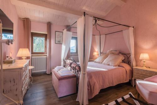 a pink bedroom with a canopy bed and a window at Agriturismo Fonte Rosa in Fiastra