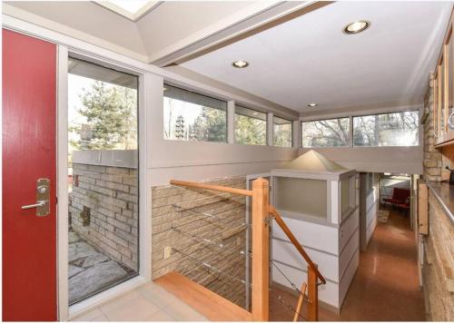 a room with a wall of windows and a staircase at Mid Century Modern Milwaukee House Spring Vacation in River Hills
