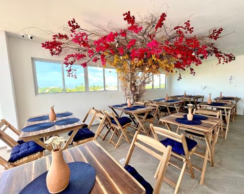 una habitación con mesas y sillas con flores rojas en Porto Vila by AFT en Porto de Galinhas