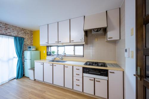 a kitchen with white cabinets and a sink and a refrigerator at VILLENT KUJUKURI MARINE in Kujukuri