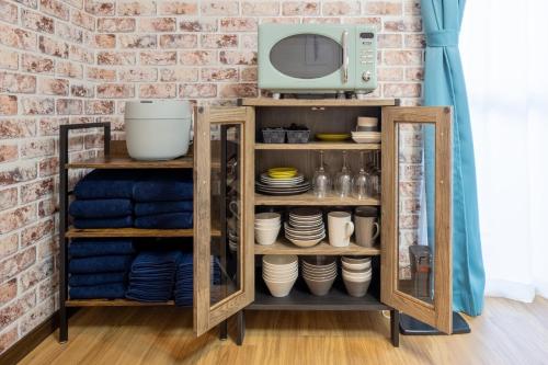 a kitchen cabinet with plates and a microwave at VILLENT KUJUKURI MARINE in Kujukuri