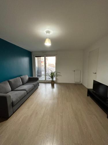 an empty living room with a couch and a television at Logement La courneuve-Aubervilliers RerB in La Courneuve