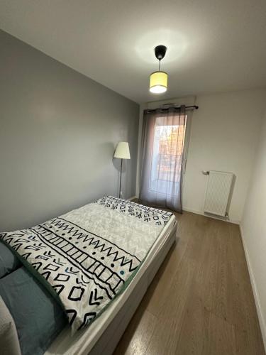 ein Schlafzimmer mit einem Bett, einer Lampe und einem Fenster in der Unterkunft Logement La courneuve-Aubervilliers RerB in La Courneuve