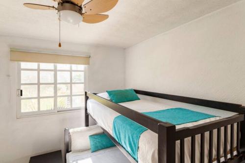 a bedroom with a bed with a ceiling fan and a window at Nuevo en Booking Casa Acapulco Diamante a Pasos de la Playa in Acapulco