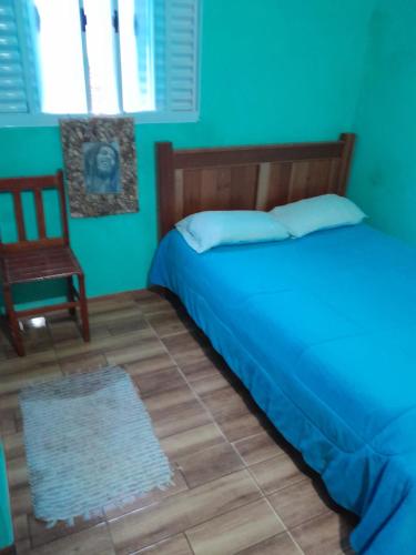 um quarto azul com uma cama e uma cadeira em Kitnet Rafael em São Thomé das Letras