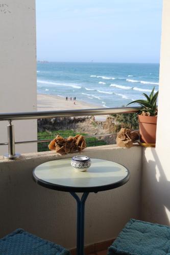 a table on a balcony with a view of the beach at Dar Marrakech Apartment Sousse in Hammam Sousse