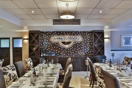 a dining room with tables and chairs and a sign on the wall at Birchwood Hotel and OR Tambo Conference Centre in Boksburg