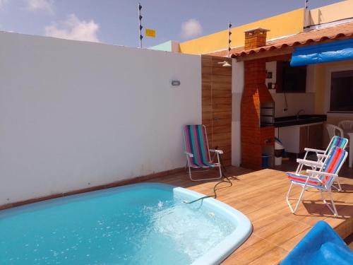 una piscina en una terraza con sillas y una casa en @vempraarembepe, en Camaçari