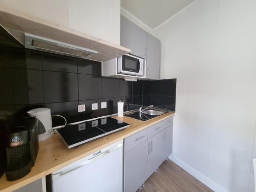 a kitchen with a sink and a microwave at Family Surf Home - Casa do Sol in Mafra