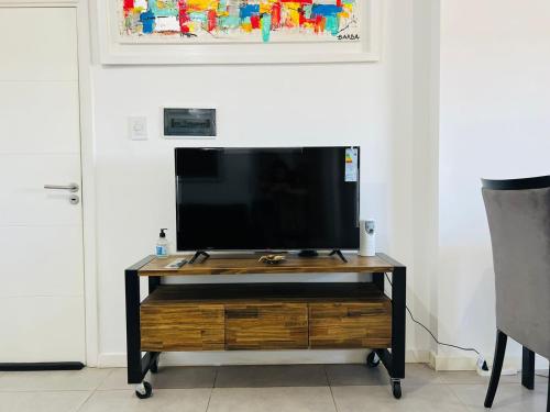 a flat screen tv sitting on top of a wooden entertainment center at DEPARTAMENTO DE 1 DORMITORIO CON VISTA A LAS SIERRAS Av Colon 5034 in Cordoba