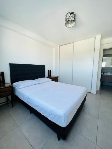 a bedroom with a white bed with a black headboard at DEPARTAMENTO DE 1 DORMITORIO CON VISTA A LAS SIERRAS Av Colon 5034 in Cordoba