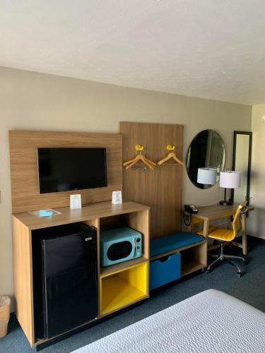 a hotel room with a television and a desk with a computer at Days Inn by Wyndham Louisville Airport Fair and Expo Center in Louisville