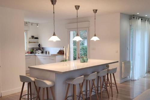 uma cozinha com uma grande ilha com bancos de bar em Villa de standing proche Airbus et Meet em Aussonne
