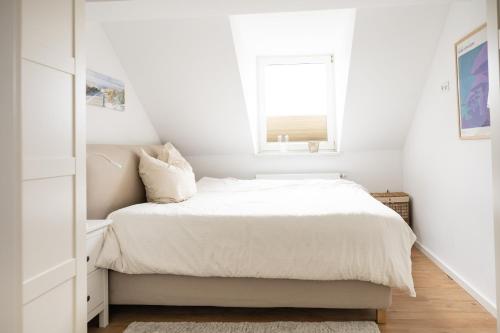 a white bedroom with a bed and a window at Ko-Living - urbanes Apartment am Zoo in Giebichenstein