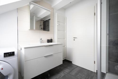 Baño blanco con lavabo y espejo en Ko-Living - urbanes Apartment am Zoo, en Giebichenstein